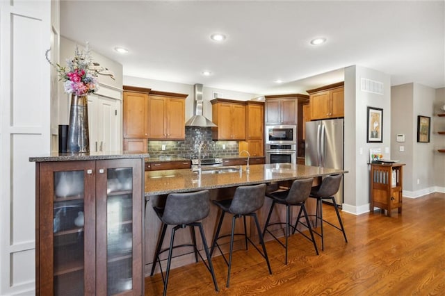 22404 S Roosevelt St, Spring Hill, KS 66083 - kitchen featuring appliances with stainless steel finishes, wall chimney exhaust hood, dark wood-style floors, brown cabinets, and a sink