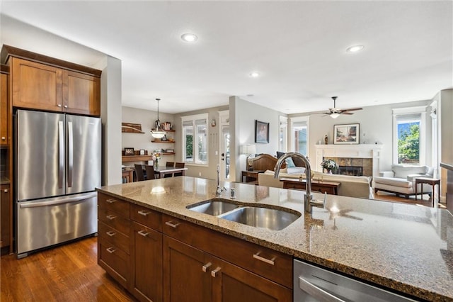 22404 S Roosevelt St, Spring Hill, KS 66083 - kitchen with stainless steel appliances, a sink, a fireplace, ceiling fan, and dark wood-style flooring