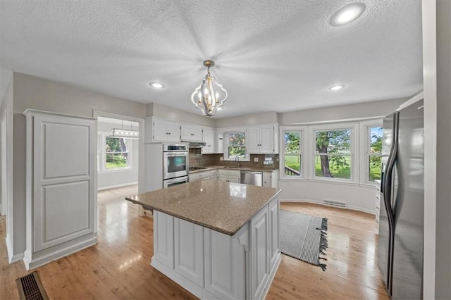 5000 W 96th St, Overland Park, KS 66207 - kitchen featuring stainless steel appliances, a sink, light wood-type flooring, a kitchen island, and white cabinetry