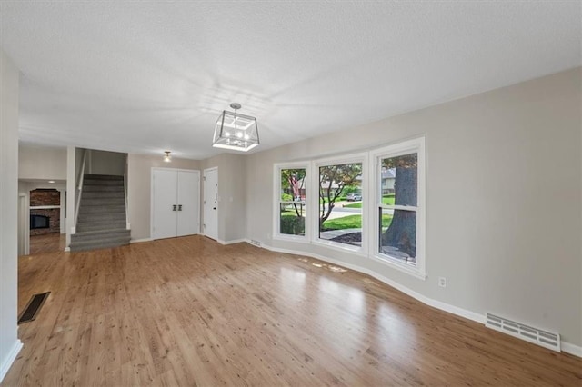 5000 W 96th St, Overland Park, KS 66207 - unfurnished living room featuring wood finished floors, a chandelier, baseboards, stairway, and a textured ceiling