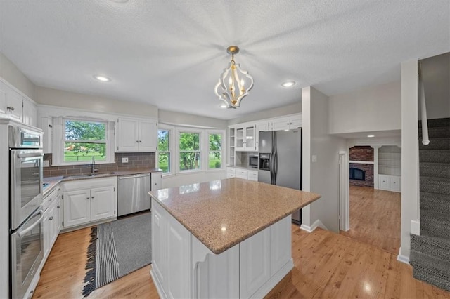 5000 W 96th St, Overland Park, KS 66207 - kitchen with appliances with stainless steel finishes, a sink, a fireplace, a kitchen island, and white cabinets