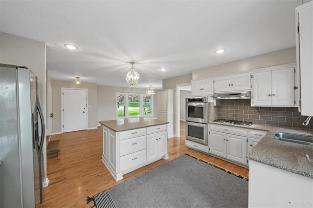 5000 W 96th St, Overland Park, KS 66207 - kitchen featuring appliances with stainless steel finishes, a sink, under cabinet range hood, light wood-style floors, and backsplash