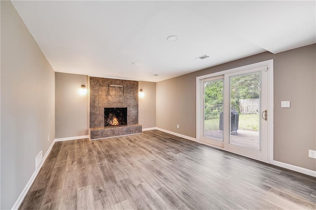 5912 E 98th St, Kansas City, MO 64134 - unfurnished living room with wood finished floors, baseboards, and a tiled fireplace
