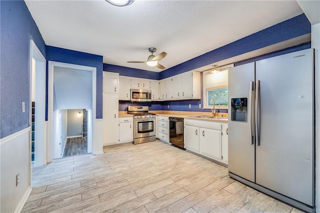 5912 E 98th St, Kansas City, MO 64134 - kitchen featuring stainless steel appliances, a sink, light wood-style flooring, light countertops, and a textured ceiling