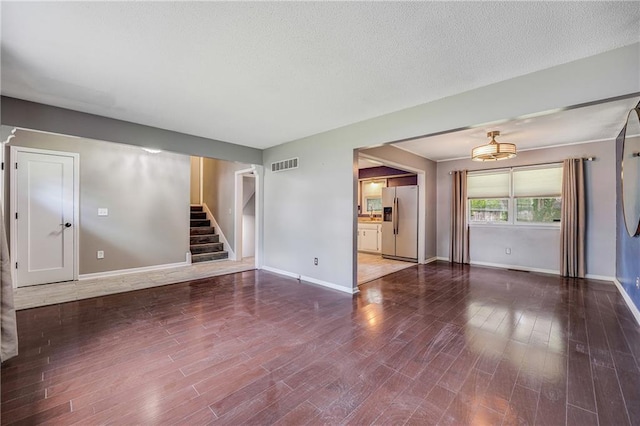 5912 E 98th St, Kansas City, MO 64134 - unfurnished living room featuring wood finished floors, stairs, baseboards, and a textured ceiling