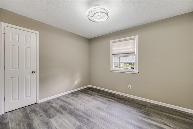5912 E 98th St, Kansas City, MO 64134 - empty room featuring baseboards, wood finished floors, and a textured ceiling