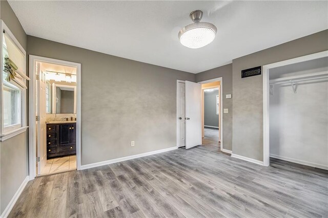 5912 E 98th St, Kansas City, MO 64134 - unfurnished bedroom featuring wood finished floors, connected bathroom, a closet, and baseboards