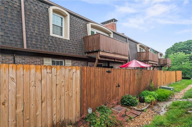 7616 W 59th Ter Unit 37, Overland Park, KS 66202 - view of side of property featuring mansard roof, brick siding, roof with shingles, and a balcony
