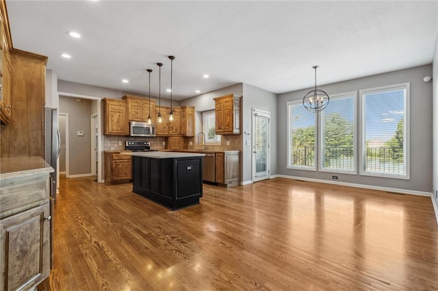 4528 N 108th St, Kansas City, KS 66109 - kitchen featuring appliances with stainless steel finishes, a sink, wood finished floors, baseboards, and a chandelier