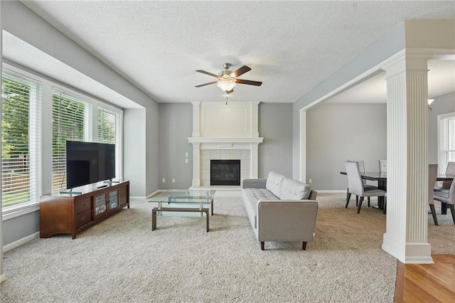 9729 Prairie Creek Rd, Lenexa, KS 66220 - carpeted living room with ornate columns, a ceiling fan, a fireplace, and a textured ceiling