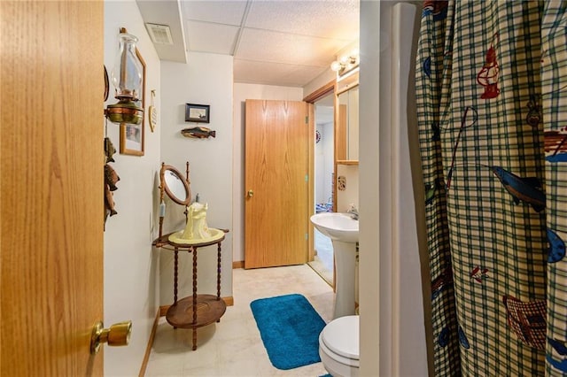 2721 SW Herefordshire Rd, Topeka, KS 66614 - bathroom featuring a drop ceiling, toilet, and baseboards