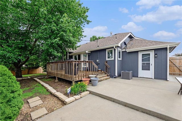 2721 SW Herefordshire Rd, Topeka, KS 66614 - back of property featuring a patio area, a wooden deck, roof with shingles, and central AC unit