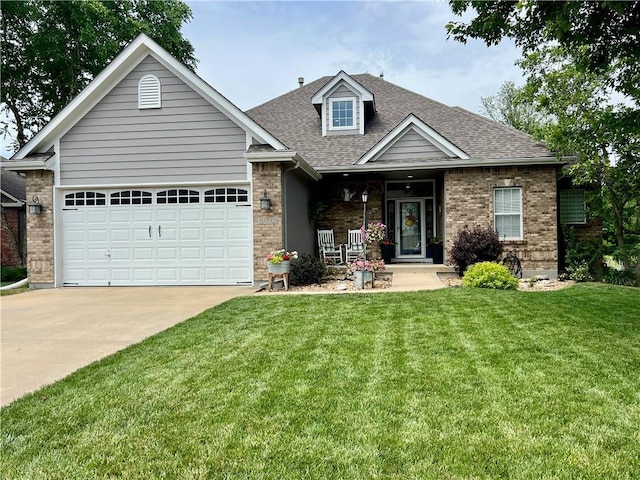 1402 NW Cedar Ct, Grain Valley, MO 64029 - view of front of property featuring concrete driveway, a front lawn, roof with shingles, brick siding, and covered porch