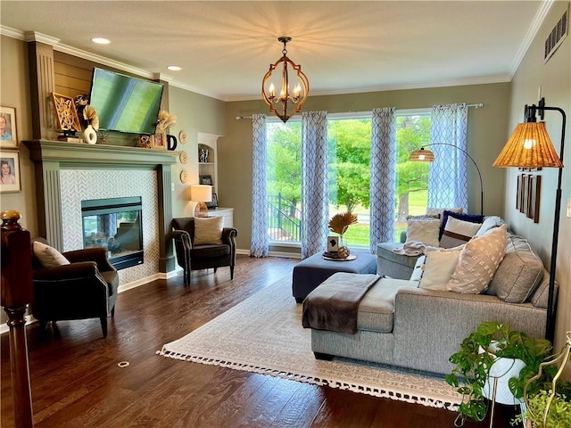 1402 NW Cedar Ct, Grain Valley, MO 64029 - living room featuring wood finished floors, ornamental molding, a chandelier, a tiled fireplace, and recessed lighting