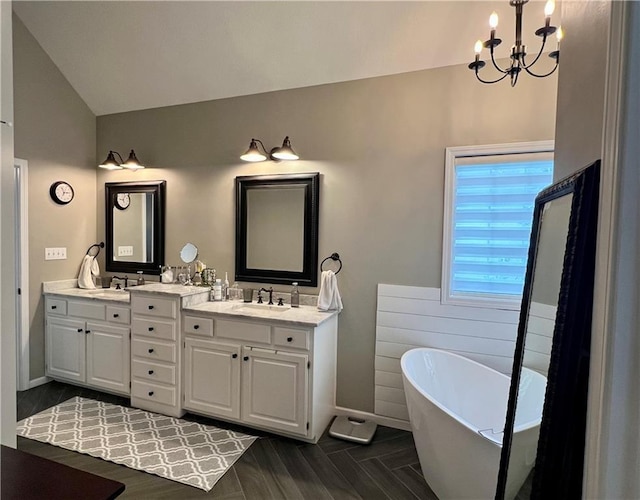 1402 NW Cedar Ct, Grain Valley, MO 64029 - bathroom featuring vaulted ceiling, a chandelier, a freestanding tub, double vanity, and baseboards