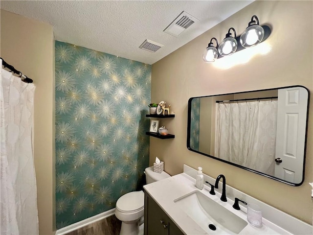 1402 NW Cedar Ct, Grain Valley, MO 64029 - full bath featuring vanity, an accent wall, toilet, a textured ceiling, and wood finished floors