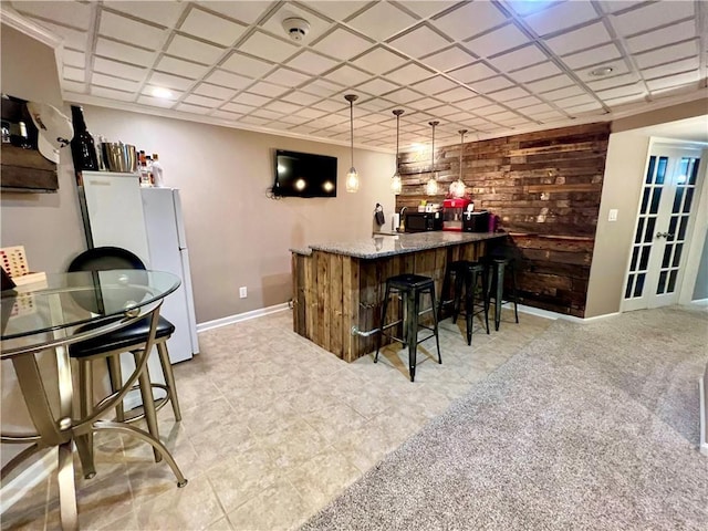 1402 NW Cedar Ct, Grain Valley, MO 64029 - indoor bar with freestanding refrigerator, black microwave, baseboards, hanging light fixtures, and wooden walls