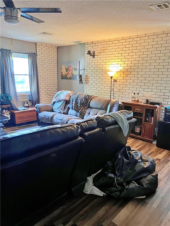 400 S 7th St, Arma, KS 66712 - living room with brick wall, light wood-style flooring, a textured ceiling, and a ceiling fan