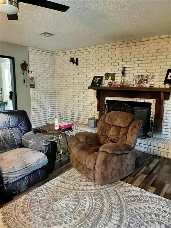400 S 7th St, Arma, KS 66712 - living room with wood finished floors, a fireplace, brick wall, and a textured ceiling