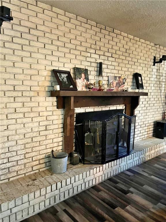 400 S 7th St, Arma, KS 66712 - detailed view of a textured ceiling, wood finished floors, brick wall, and a fireplace