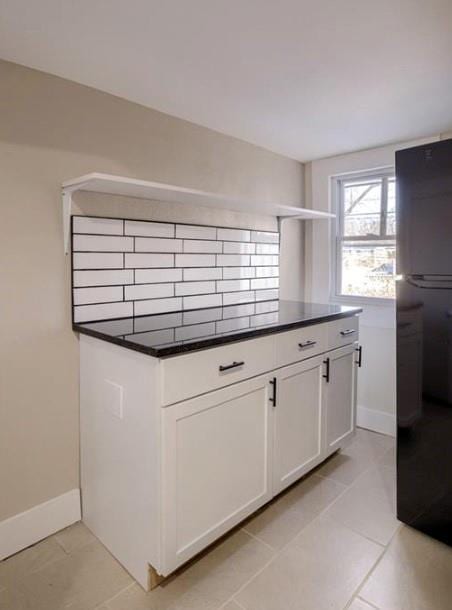 4204 E 60th Ter, Kansas City, MO 64130 - kitchen featuring freestanding refrigerator, dark countertops, baseboards, and white cabinetry
