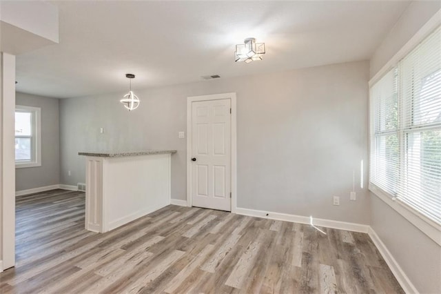 7119 E 111th Ter, Kansas City, MO 64134 - spare room featuring light wood-style floors, baseboards, and a chandelier