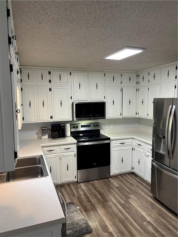 1015 S Elm St, Ottawa, KS 66067 - kitchen with stainless steel appliances, a sink, a textured ceiling, white cabinets, and dark wood-type flooring