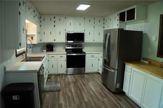 1015 S Elm St, Ottawa, KS 66067 - kitchen with stainless steel appliances, a sink, white cabinets, light countertops, and dark wood finished floors