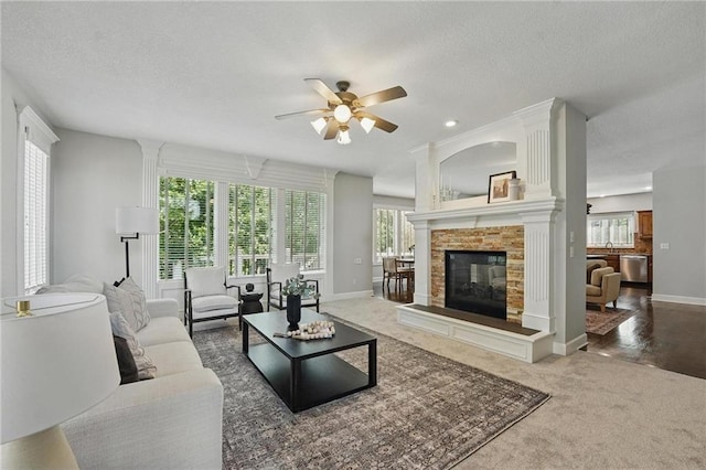 7407 W 145th Ter, Overland Park, KS 66223 - carpeted living room with a ceiling fan, healthy amount of natural light, baseboards, a textured ceiling, and a tiled fireplace