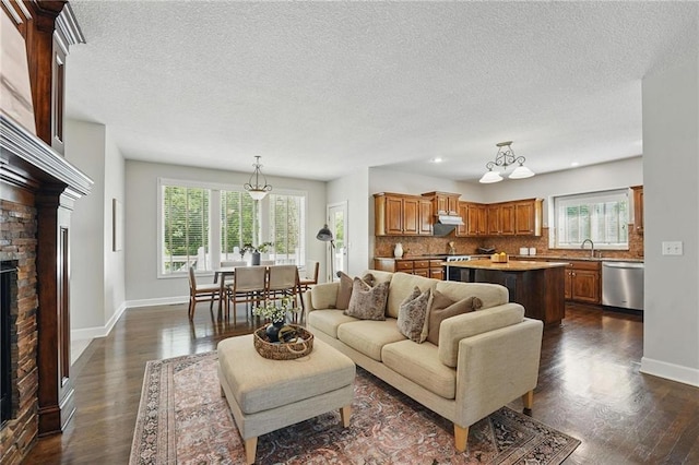 7407 W 145th Ter, Overland Park, KS 66223 - living room with dark wood-style floors, a stone fireplace, plenty of natural light, a textured ceiling, and baseboards