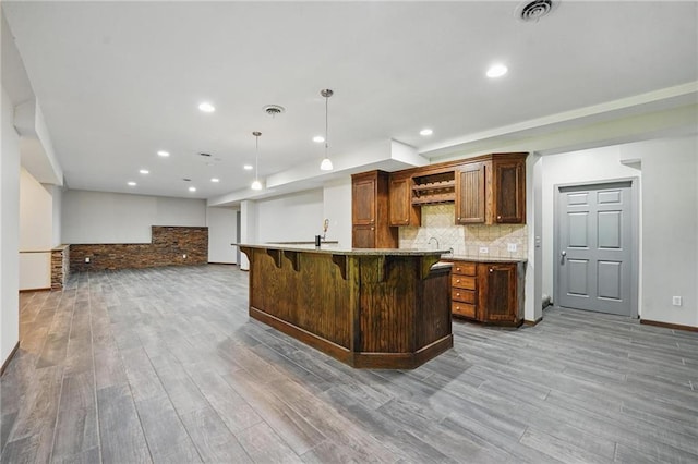 7407 W 145th Ter, Overland Park, KS 66223 - kitchen with wood finished floors, a kitchen breakfast bar, open shelves, an island with sink, and recessed lighting