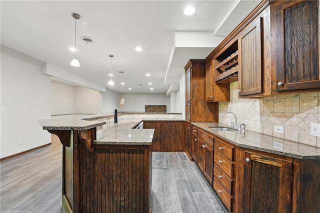 7407 W 145th Ter, Overland Park, KS 66223 - kitchen with a sink, light wood-style flooring, decorative backsplash, light stone countertops, and recessed lighting