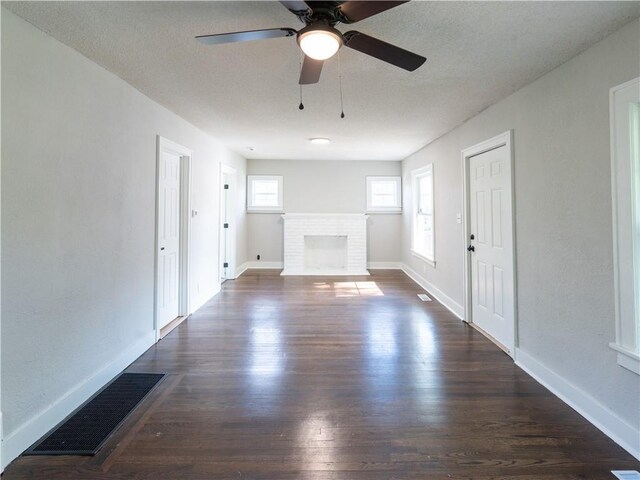 4941 Park Ave, Kansas City, MO 64130 - unfurnished living room with dark wood-style floors, a fireplace, a ceiling fan, and baseboards