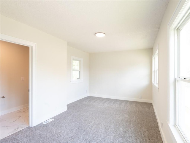 4941 Park Ave, Kansas City, MO 64130 - spare room featuring baseboards, marble look tile flooring, and carpet