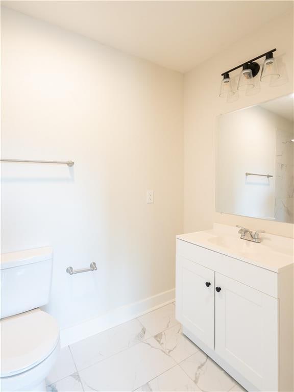 4941 Park Ave, Kansas City, MO 64130 - bathroom featuring marble look tiles, baseboards, toilet, and vanity