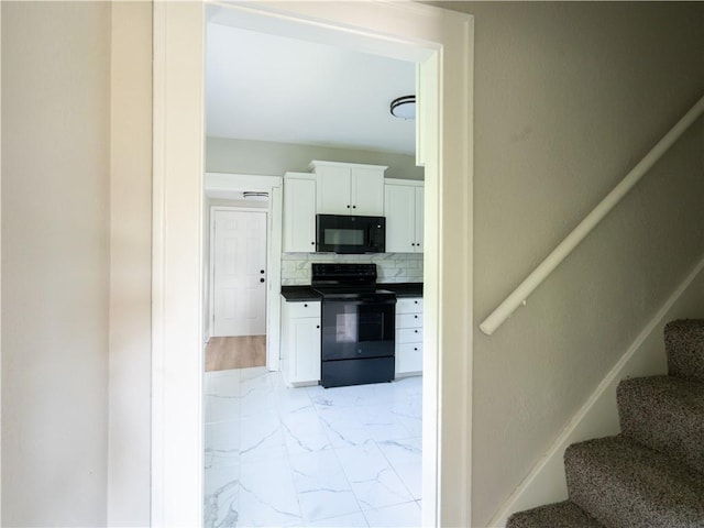 4941 Park Ave, Kansas City, MO 64130 - kitchen featuring black appliances, light marble finish flooring, white cabinets, dark countertops, and decorative backsplash