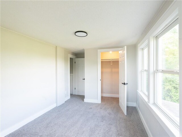 4941 Park Ave, Kansas City, MO 64130 - unfurnished bedroom with light colored carpet, baseboards, multiple windows, and a walk in closet