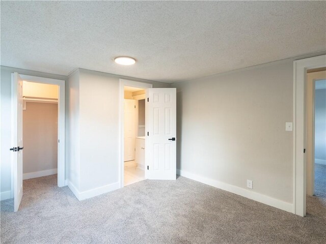 4941 Park Ave, Kansas City, MO 64130 - unfurnished bedroom with carpet flooring, baseboards, a textured ceiling, and a walk in closet