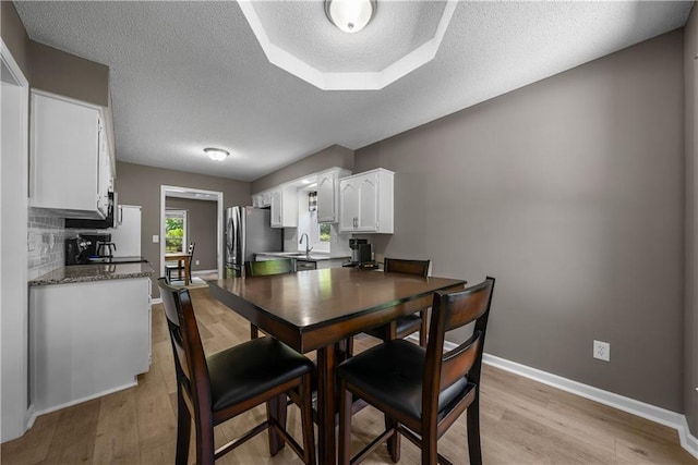 1728 SE 7th Ter, Lees Summit, MO 64063 - dining area with light wood-style floors, a textured ceiling, and baseboards