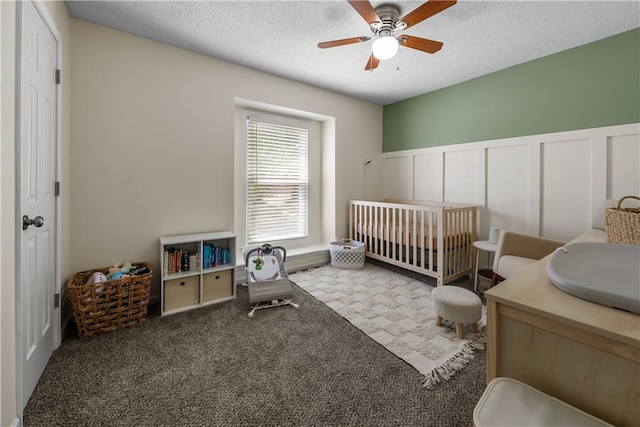 1728 SE 7th Ter, Lees Summit, MO 64063 - carpeted bedroom with a wainscoted wall, a textured ceiling, a crib, a decorative wall, and ceiling fan