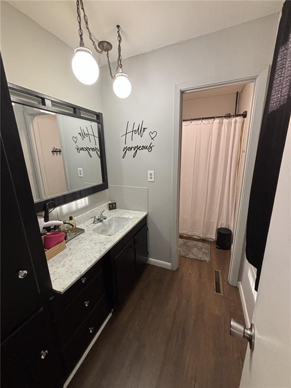 611 W Main St, Chanute, KS 66720 - bathroom with wood finished floors, vanity, baseboards, and a shower with curtain