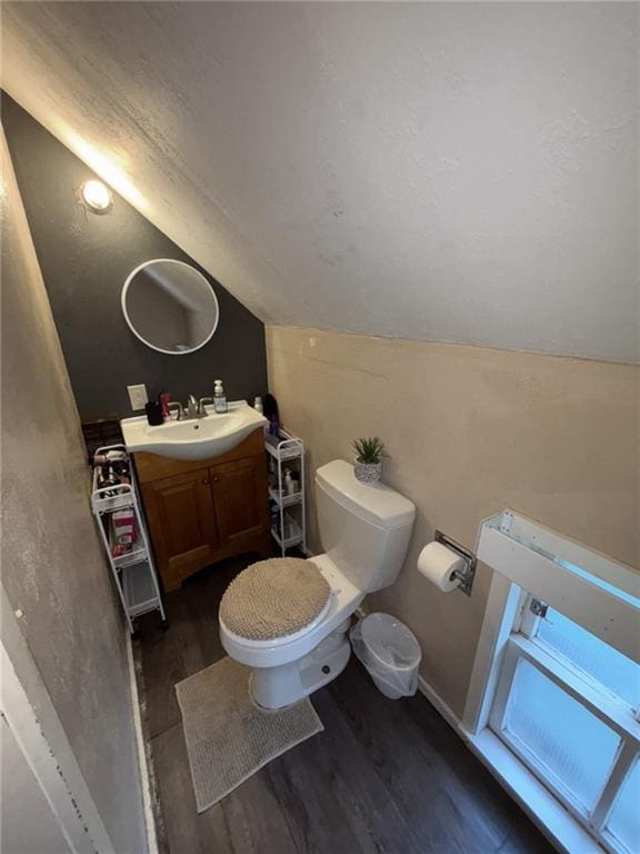 611 W Main St, Chanute, KS 66720 - half bathroom featuring lofted ceiling, vanity, toilet, and wood finished floors