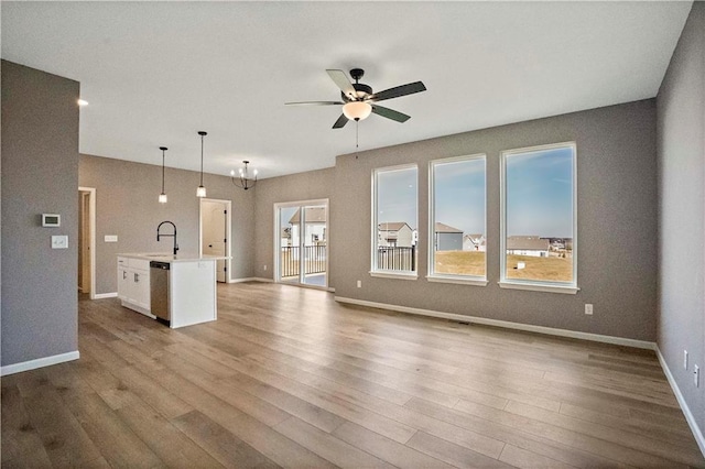 12513 S White Ash Ln, Lees Summit, MO 64086 - unfurnished living room featuring a sink, healthy amount of natural light, a ceiling fan, and baseboards