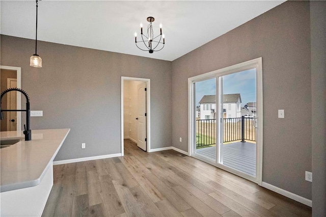12513 S White Ash Ln, Lees Summit, MO 64086 - unfurnished dining area with a chandelier, wood finished floors, baseboards, and a sink