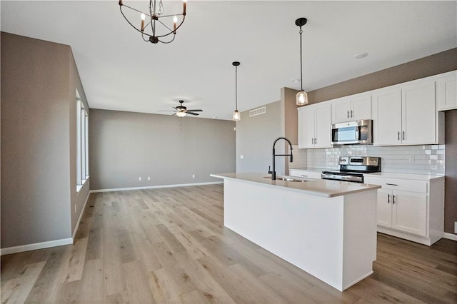 12513 S White Ash Ln, Lees Summit, MO 64086 - kitchen featuring stainless steel appliances, tasteful backsplash, light wood-style floors, and white cabinets