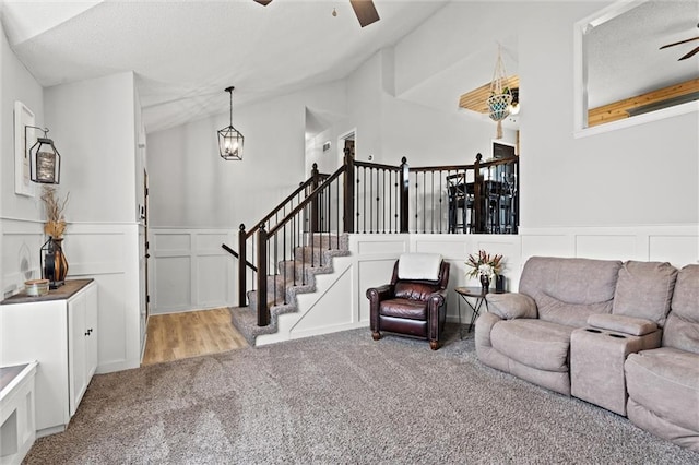8801 NE 116th St, Kansas City, MO 64157 - living room featuring a ceiling fan, carpet, a decorative wall, a wainscoted wall, and vaulted ceiling