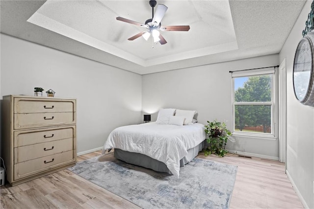 8801 NE 116th St, Kansas City, MO 64157 - bedroom featuring a raised ceiling, light wood-type flooring, ceiling fan, and a textured ceiling