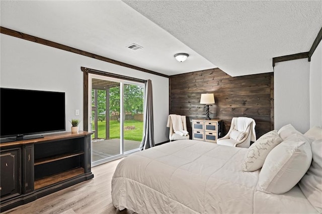 8801 NE 116th St, Kansas City, MO 64157 - bedroom with access to outside, wood walls, light wood-style flooring, a textured ceiling, and an accent wall