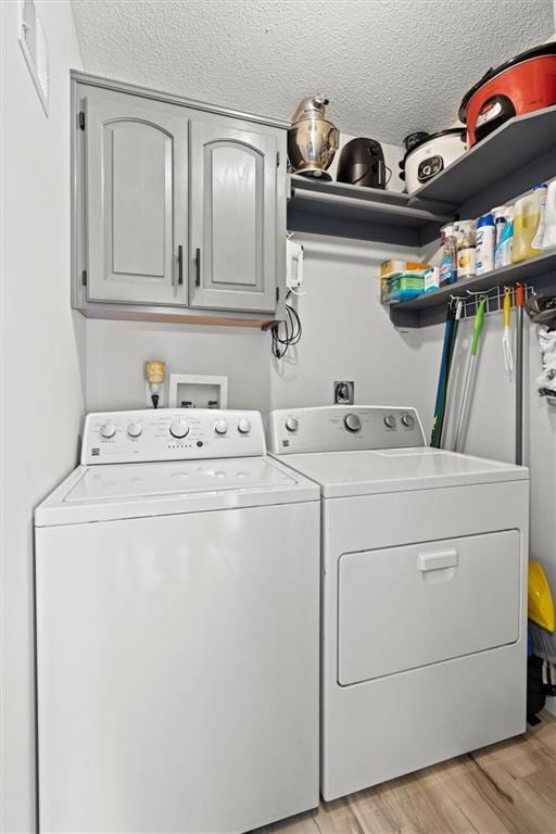 8801 NE 116th St, Kansas City, MO 64157 - laundry room featuring cabinet space, separate washer and dryer, light wood finished floors, and a textured ceiling