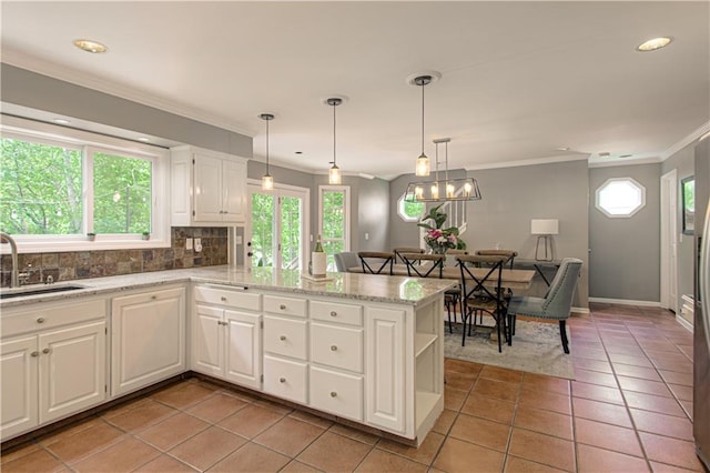 601 NW 41st St, Kansas City, MO 64116 - kitchen featuring a sink, ornamental molding, white cabinetry, a peninsula, and decorative backsplash